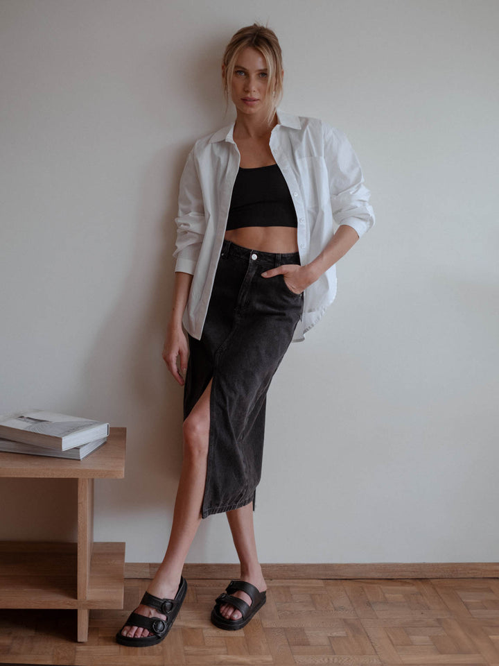 Vista completa de look casual usando crop top negro, falda larga del mismo tono y camiseta blanca.