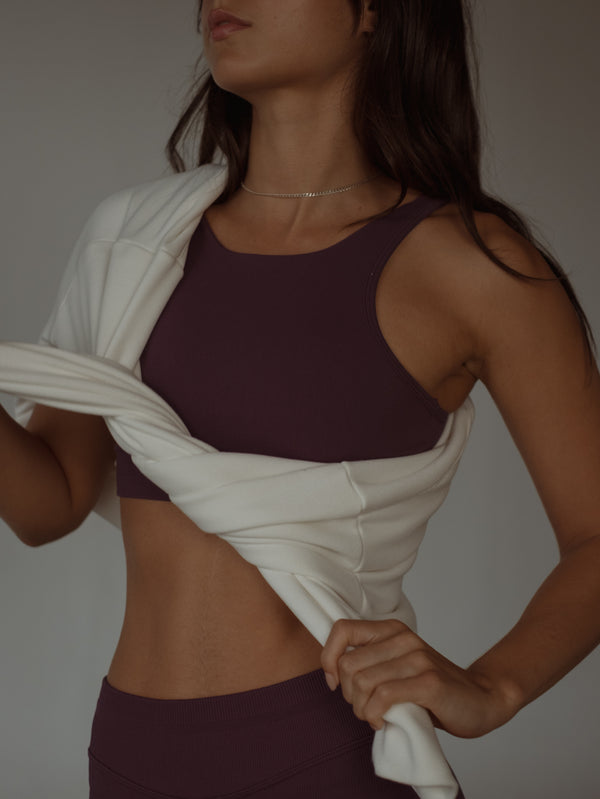 Modelo usando buzo crudo amarrado con top deportivo vino sin costuras.