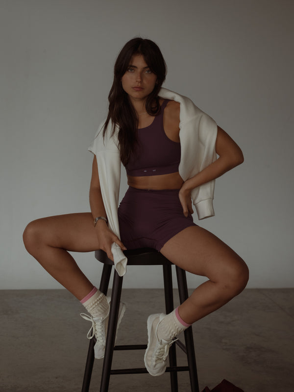 Modelo usando ropa deportiva vino sin costuras con buzo crudo y medias.