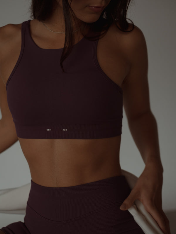 Modelo usando top deportivo halter vino sin costuras en poliamida.