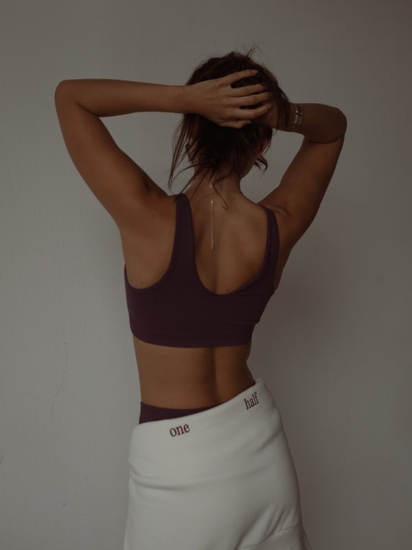 Vista posterior modelo usando top deportivo halter color vino.
