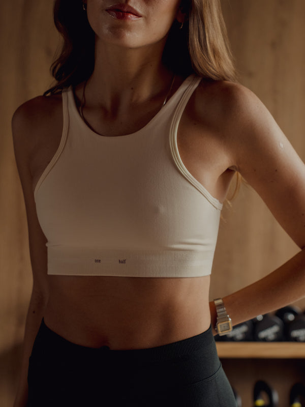 Modelo usando top deportivo crema estilo halter con ajuste medio.