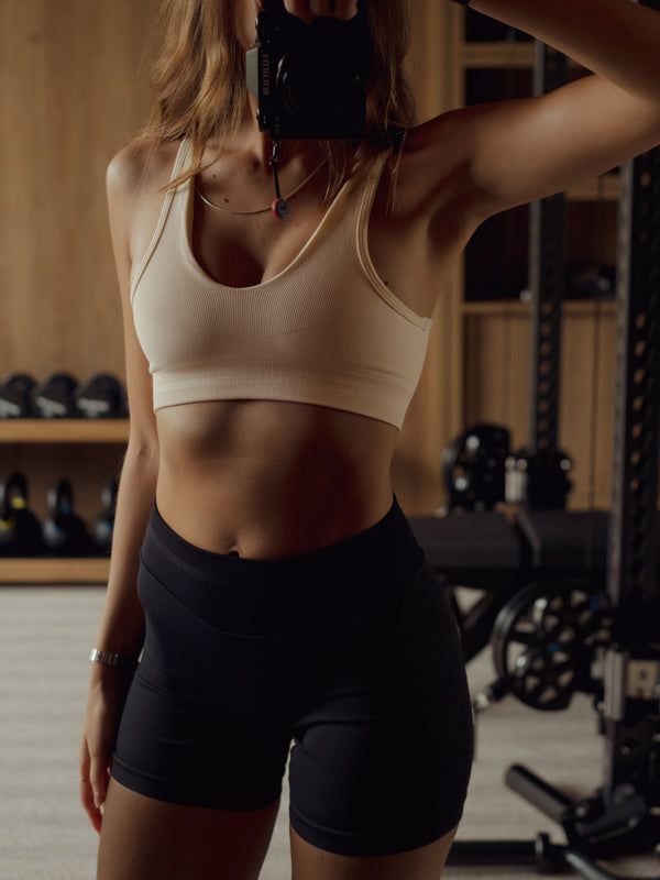 Modelo usando top deportivo crema ajuste medio en poliamida.