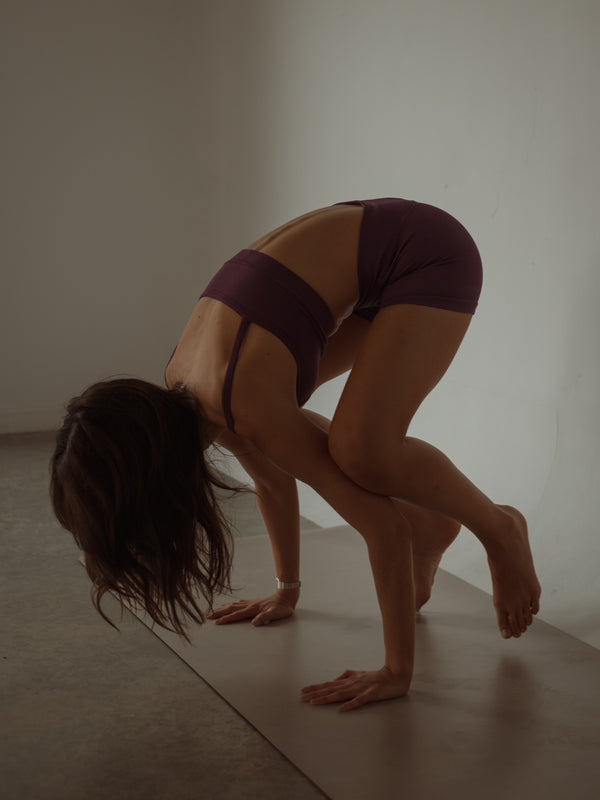 Modelo haciendo yoga con ropa deportiva vino de secado rápido.