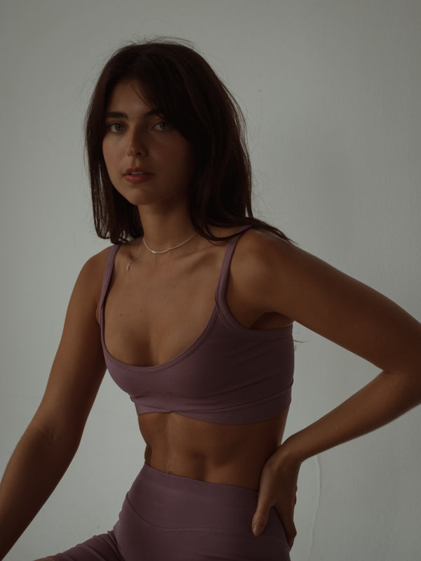 Modelo con top deportivo de tiras asimétrico en poliamida color rosado.