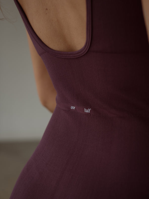 Vista a detalle de estampado "One Half" de enterizo deportivo vino.