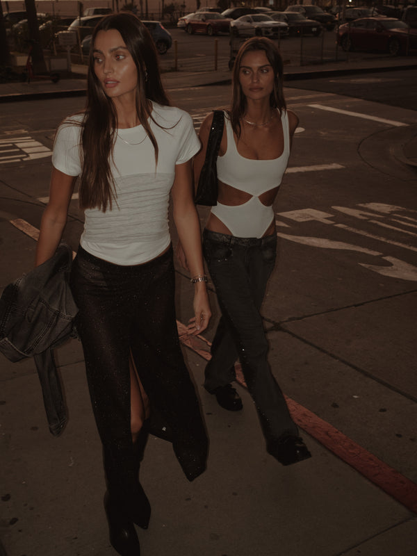 Dos modelos caminando en estacionamiento con looks de noche.