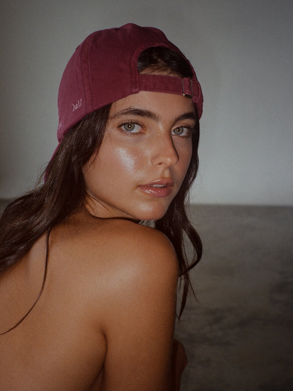 Modelo usando gorra clásica color vino hacia atrás con ajuste posterior.