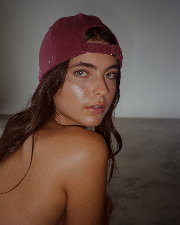 Modelo usando gorra clásica color vino hacia atrás con ajuste posterior.