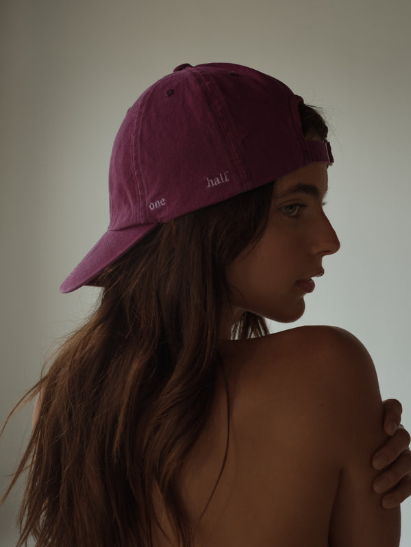 Vista posterior modelo usando gorra clásica vino con bordado "One Half".