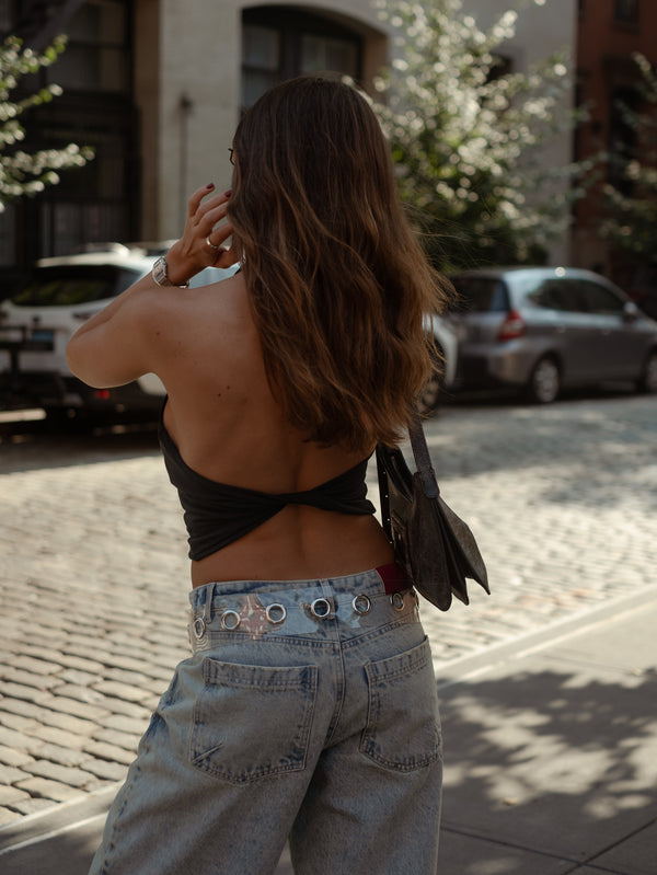 Vista detallada espalda cruzada de top negro con jean azul vintage.  