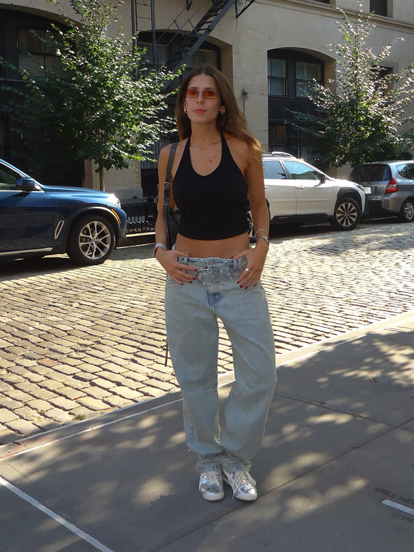 Modelo en la calle vistiendo top negro con jean ancho y tenis. 