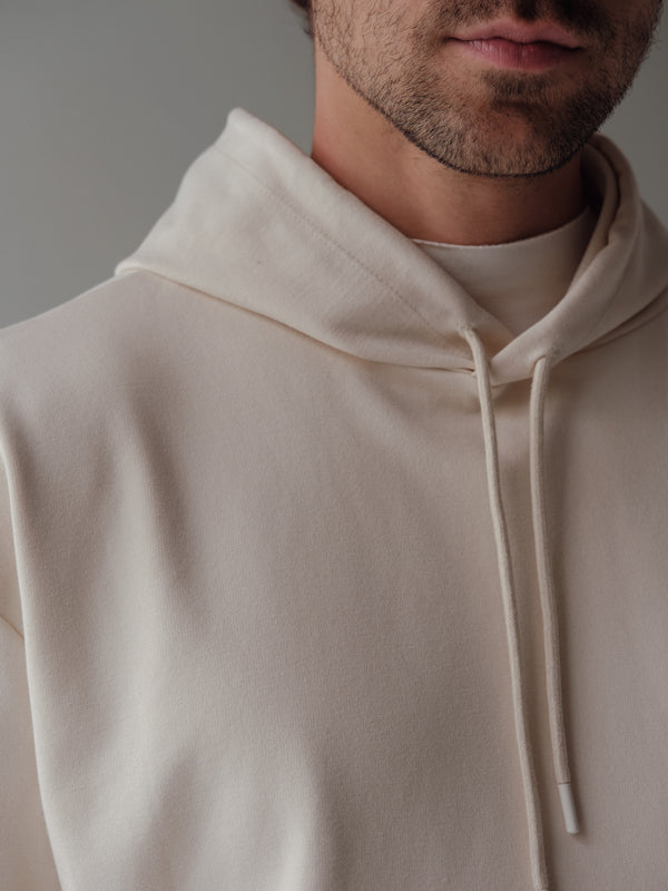 Vista a detalle de cordón en capucha de buzo crema para hombre.