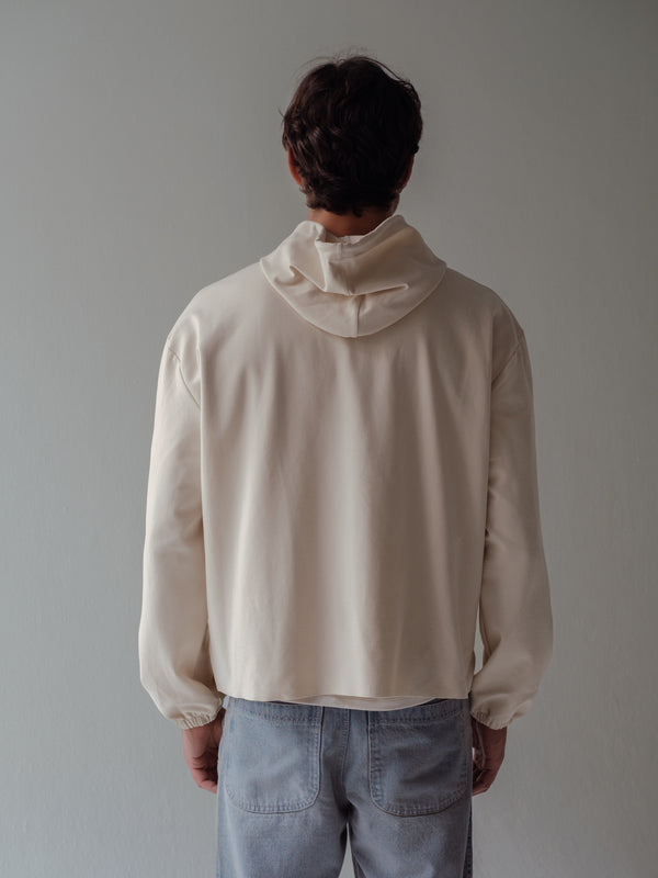 Vista posterior de buzo crema con capucha.