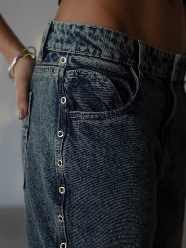 Vista a detalle de apliques metálicos de jean azul.