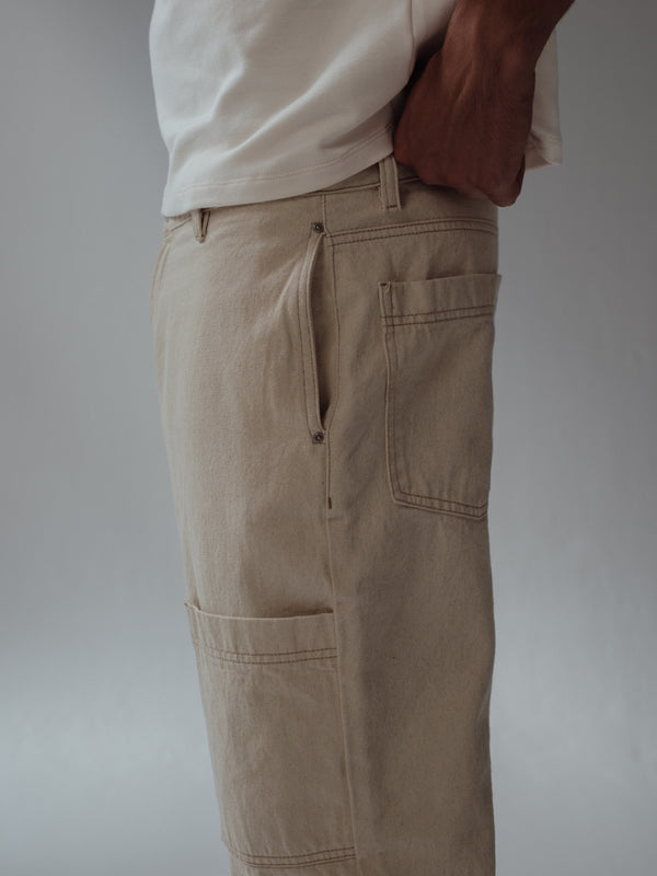 Vista lateral a detalle de bolsillos laterales, posteriores y frontales de jean crema. 