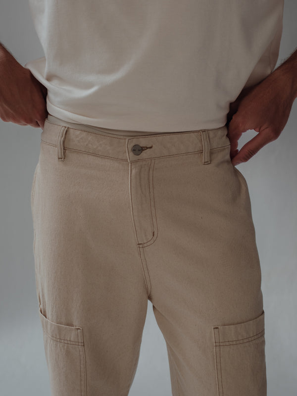 Vista a detalle botón frontal de jean crema con bolsillos frontales tipo cargo.