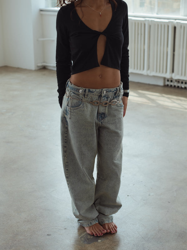 Look casual jean azul claro ancho con top manga larga negro con escote en nudo. 