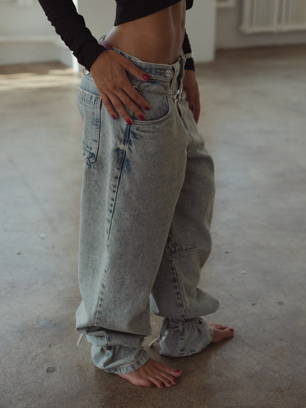 Vista lateral jean azul claro con tiras para amarrar la bota.