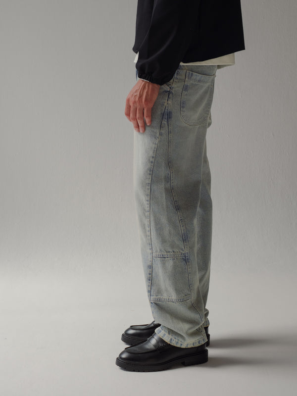 Vista lateral de jean azul claro bota recta con costuras asimétricas. 