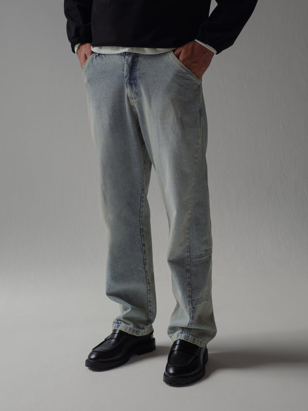 Jean azul con lavado ahumado y costuras visibles en la bota. 