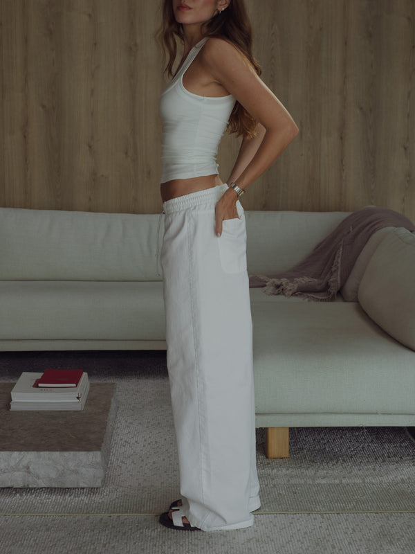 Vista lateral modelo con jean de algodón crudo con top manga sisa.