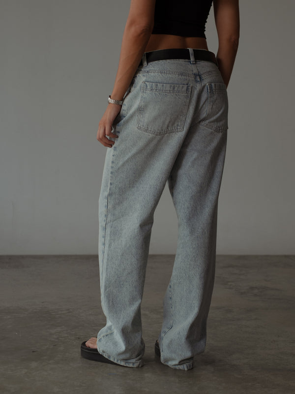 Vista posterior modelo con jean clásico azul claro con cinturón negro.