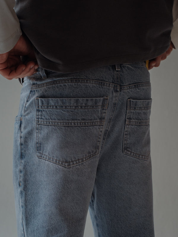 Vista a detalle bolsillos posteriores jean azul claro para hombre. 