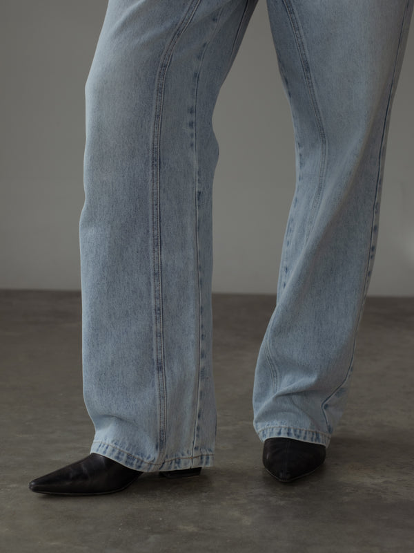 Vista a detalle de costuras visibles en bota de jean azul claro.