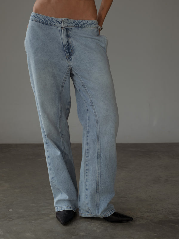 Vista frontal de jean azul claro con pretina delgada y costuras visibles.