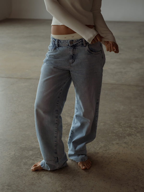 Vista frontal de jean azul bota ancha con pantie y top manga larga crudo.