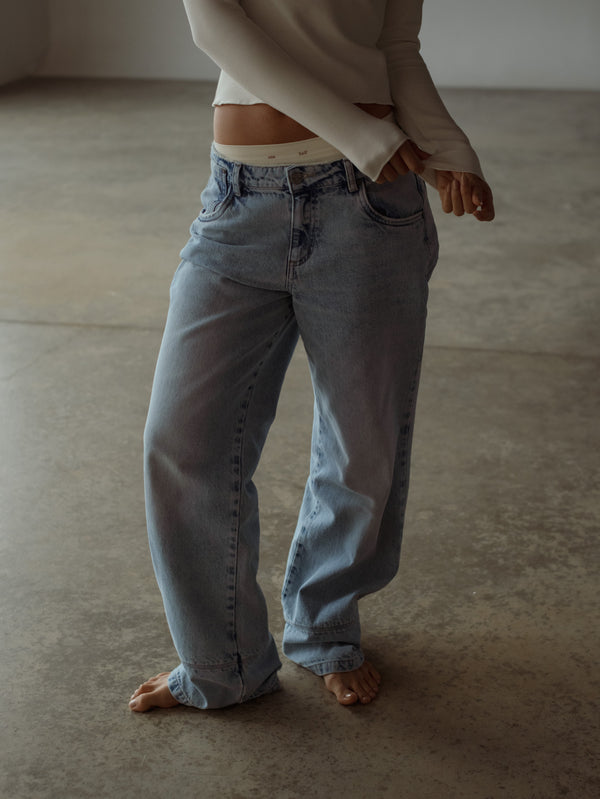 Vista frontal de jean azul bota ancha con pantie y top manga larga crudo.