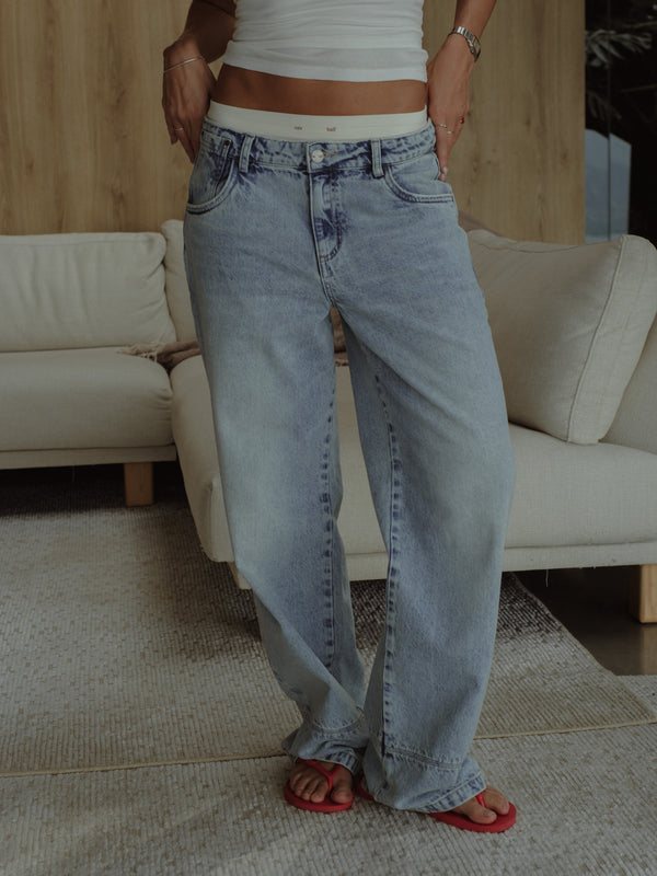 Modelo usando jean azul lavado clásico con pantie crudo y top crema.