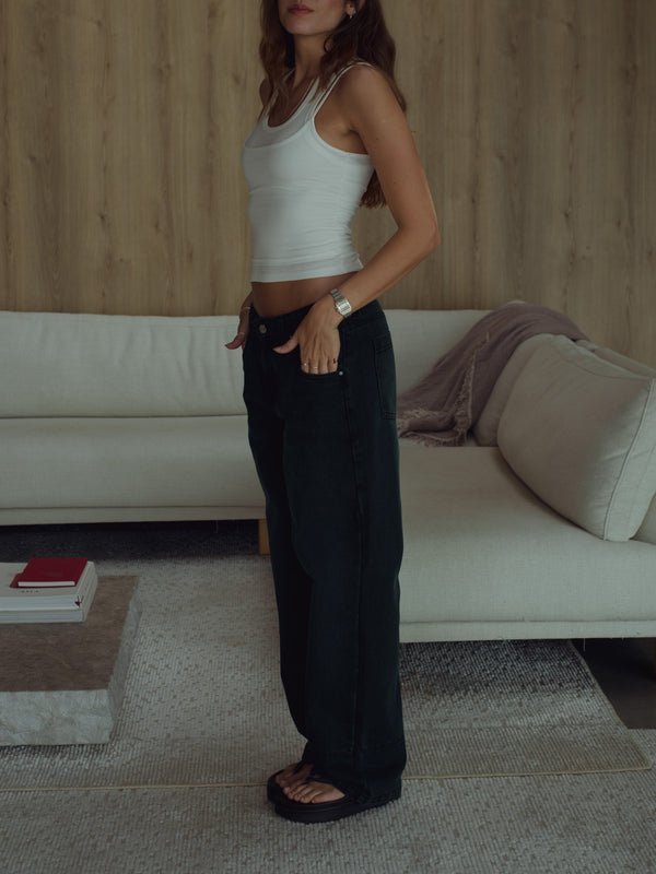 Modelo usando jean negro azul con top crema y sandalias. 