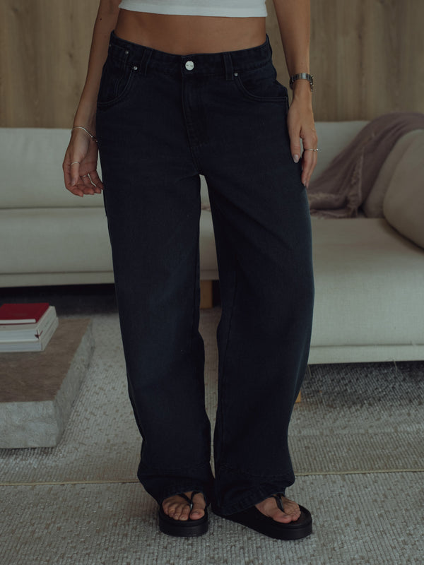 Vista frontal jean negro azul para mujer con sandalias.