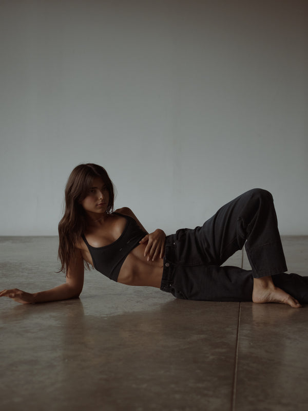 Modelo usando top deportivo negro con jean negro azul oscuro.