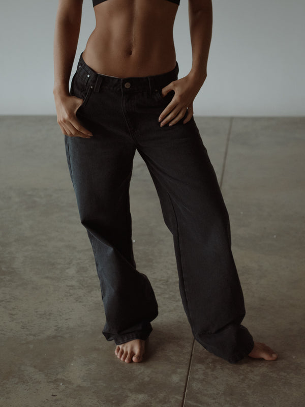 Modelo usando jean negro azul para mujer estilo tiro bajo.