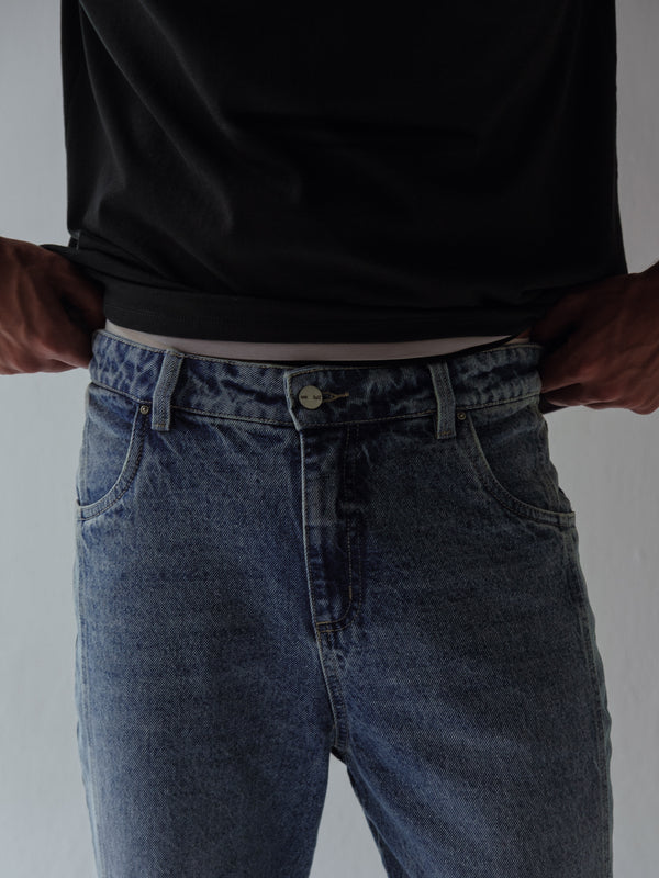 Vista frontal a detalle pretina de jean azul clásico para hombre. 