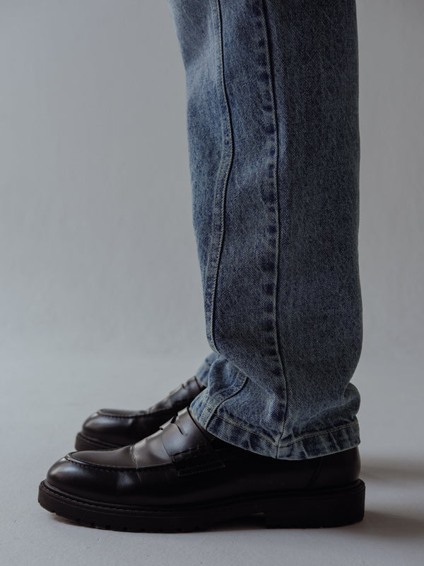 Vista a detalle lateral de bota de jean azul clásico para hombre. 