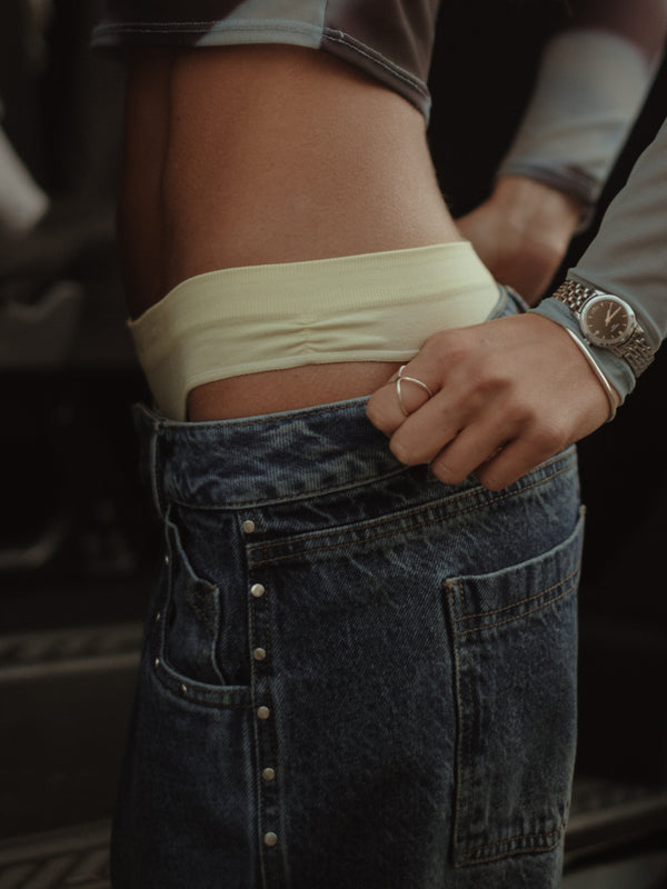 Modelo con pantie amarillo y jean azul con apliques laterales.