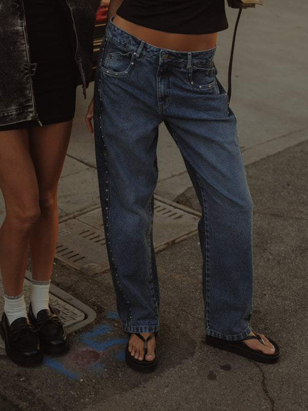 Modelo con jean bota recta en dos tonos de azul con apliques metálicos.