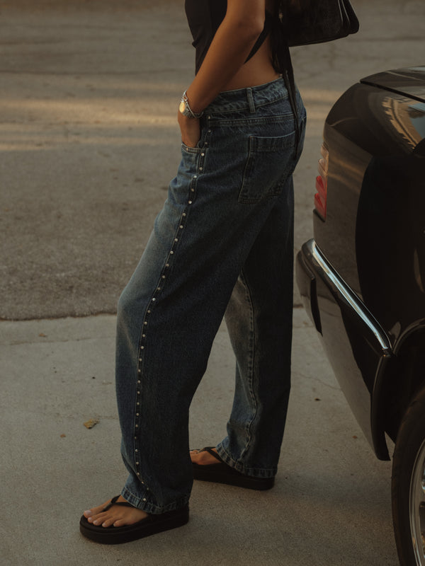 Vista lateral jean bota recta en dos tonos de azul con apliques metálicos.