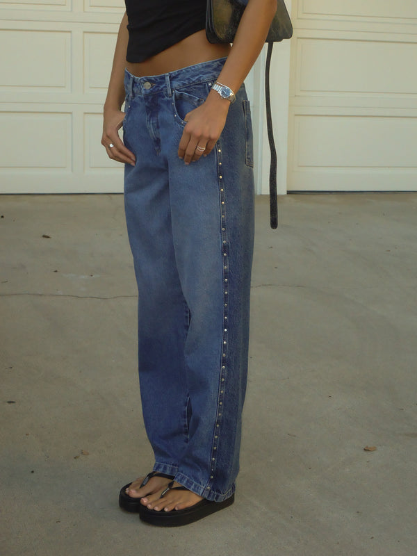 Modelo con jean bota recta en dos tonos de azul con apliques metálicos.