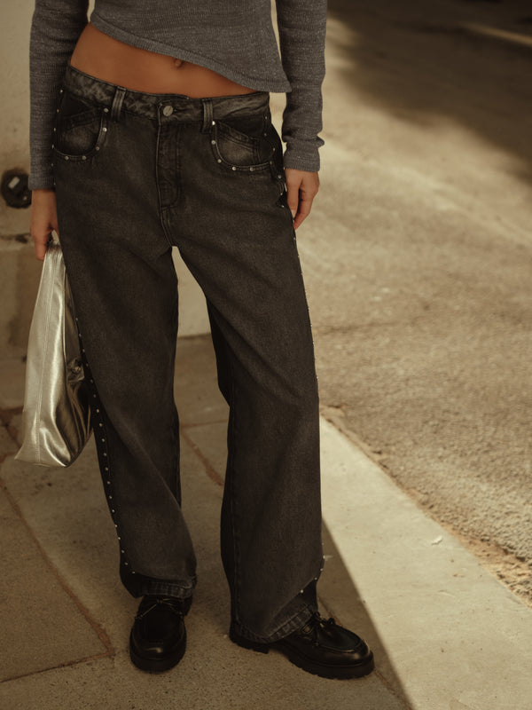 Modelo usando jean gris con apliques metálicos y bolso lata.