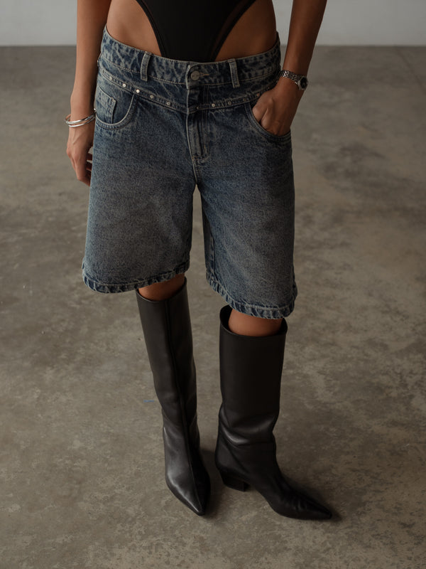 Vista frontal short doble pretina con apliques metálicos con bodie negro.