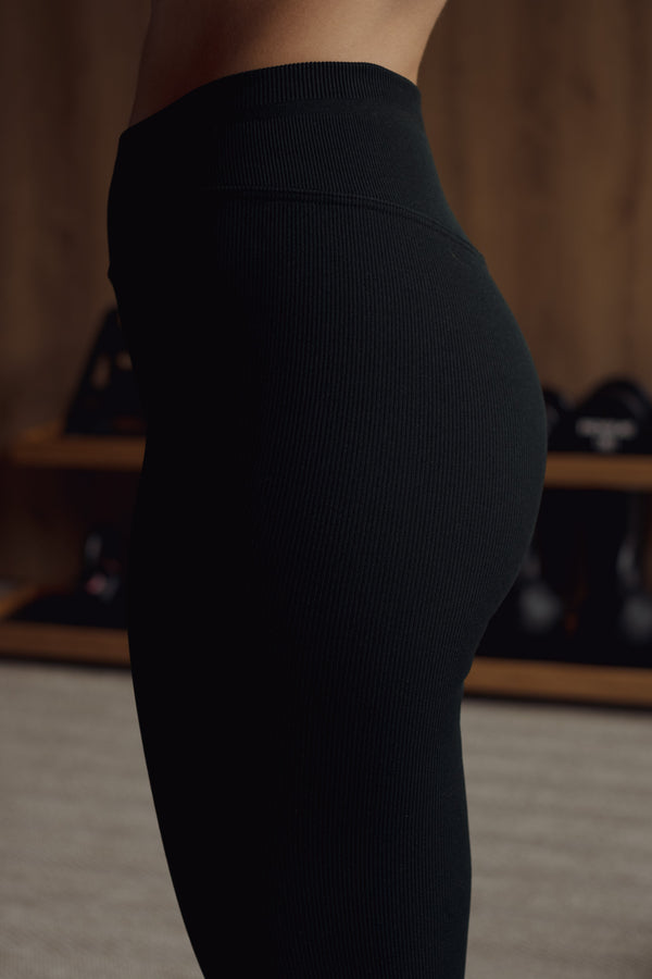 Vista posterior de leggings deportivo negro sin costuras en poliamida.