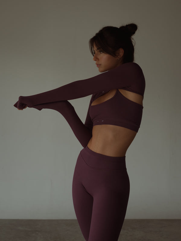 Modelo usando ropa deportiva vino con mangas deportivas en poliamida.