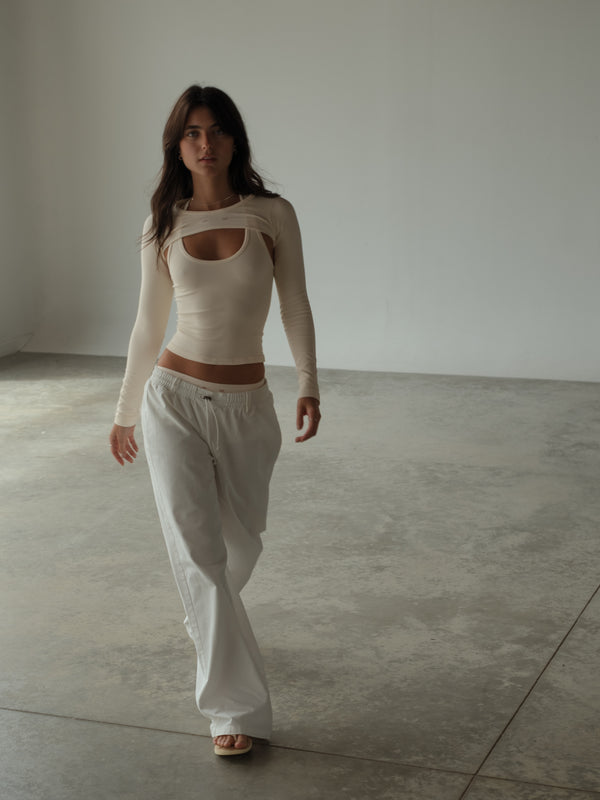 Vista frontal modelo usando ropa deportiva con mangas crema.