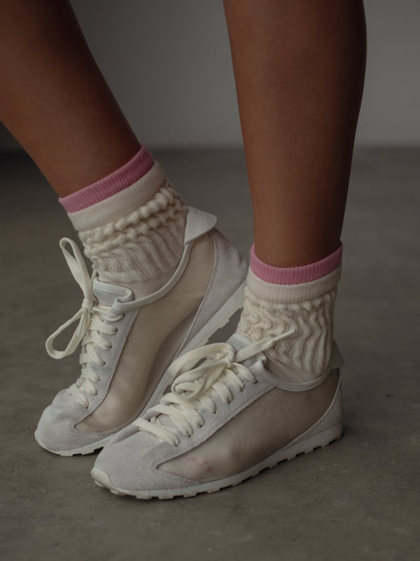 Modelo usando tenis grises con medias deportivas crema con rosa.