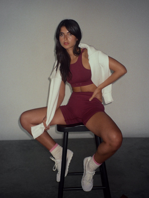 Modelo usando ropa deportiva vino para mujer con medias crema y rosa.